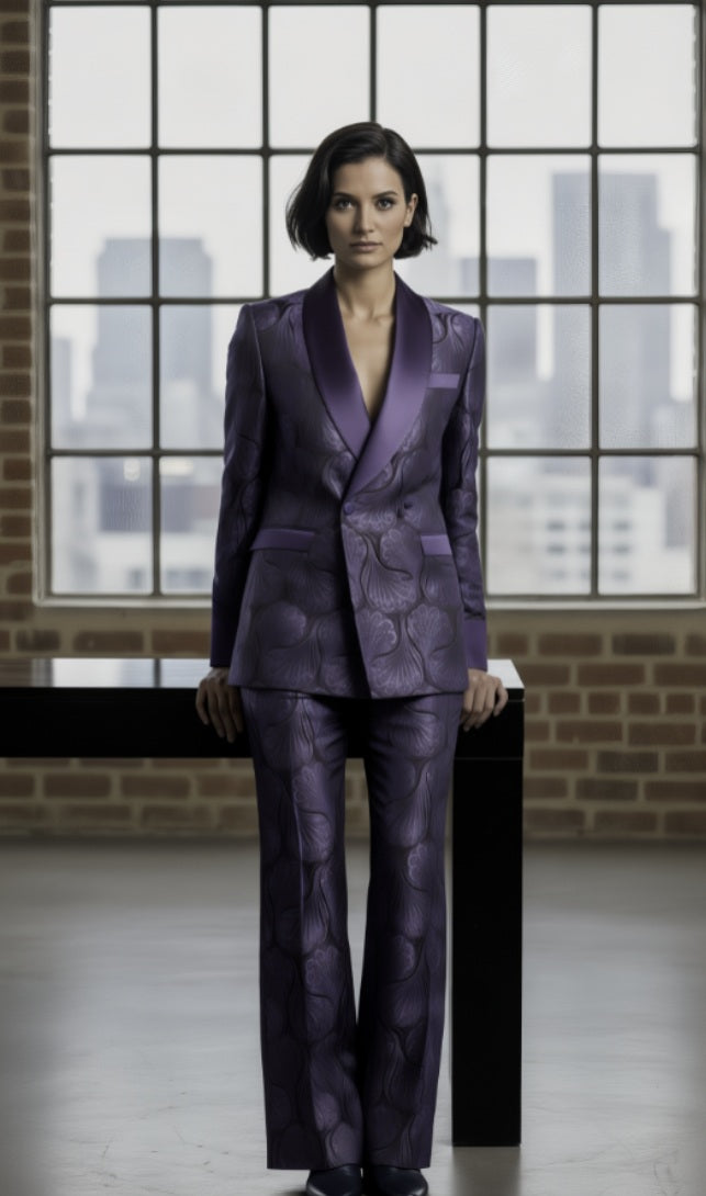 Woman wearing a purple patterned suit standing in front of a large window with cityscape view.