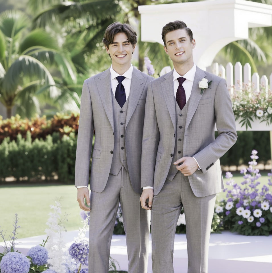 Two men in grey suits standing outdoors with flowers and greenery in the background