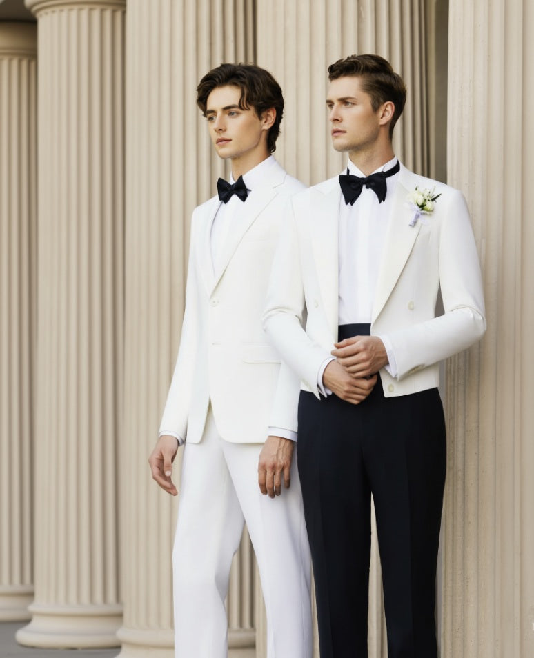 Two men wearing white evening jackets with black trousers, standing in a columned hallway.