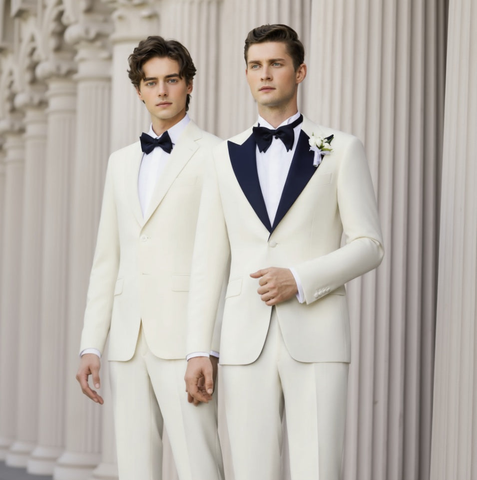 Two men wearing white evening suits with navy lapels, one jacket and one trousers, standing in a columned room.