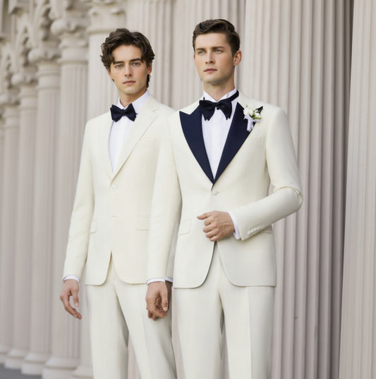 Two men wearing white evening suits with navy lapels, one jacket and one trousers, standing in a columned room.