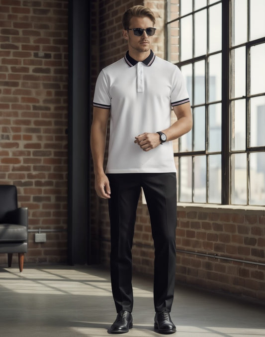 Man wearing a white polo shirt with black accents and black pants in an industrial-style room.