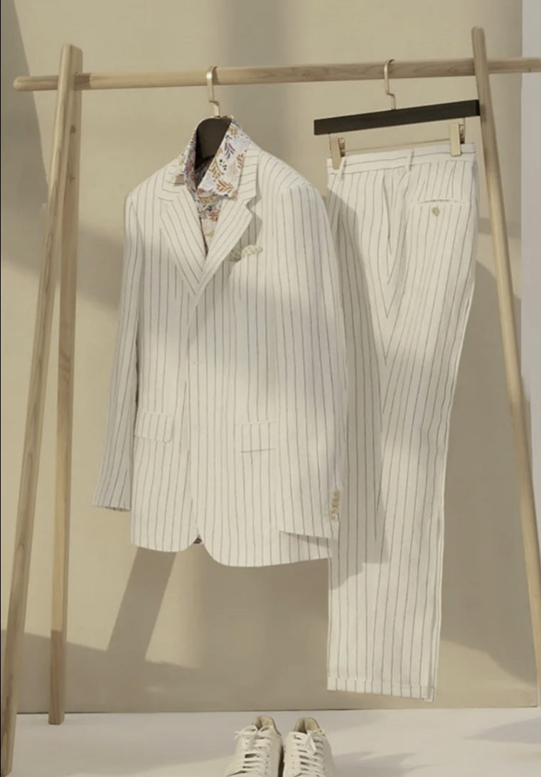 White pinstripe suit with floral shirt on a wooden rack against a beige background