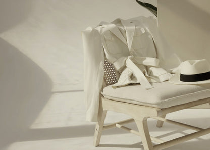 White shirt on a chair with a black belt, against a neutral background