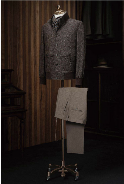 A brown check casual jacket and brown trousers displayed on a mannequin against a background of a wood-paneled room with dark brown furniture.