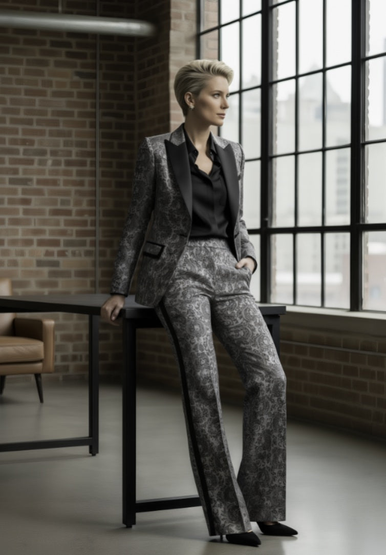 Person wearing a gray suit sitting in a room with large windows and brick walls.