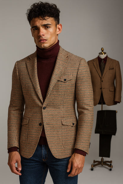 Man wearing a brown checkered blazer over a maroon turtleneck with a gray background.