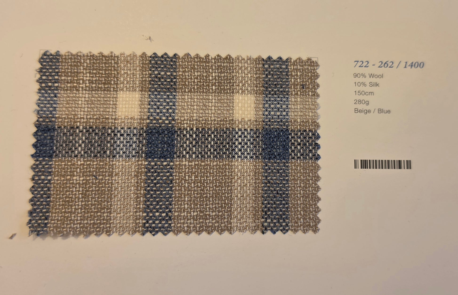 square fabric swatch with a blue and beige plaid pattern, displayed on a white background next to printed text detailing its composition and color.